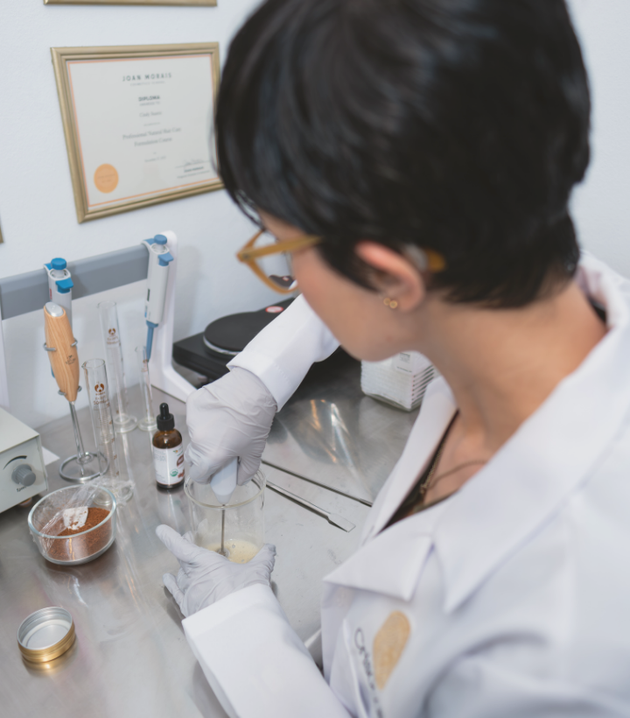 Cindy Suárez, Professional Hair Care formulator is creating a BotaniReset Hair Balm formula in a lab setting.