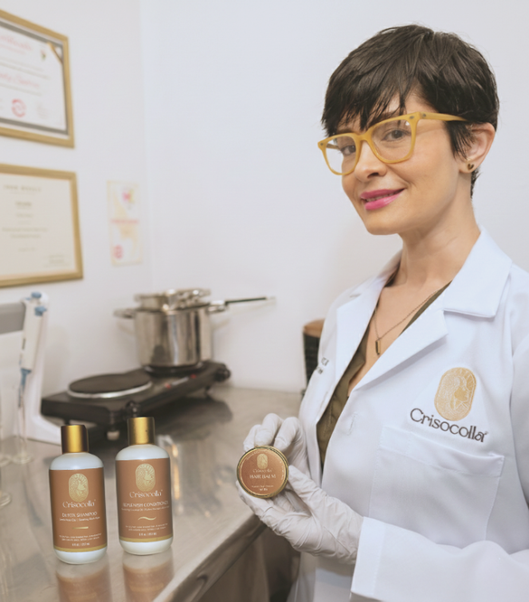 Cindy Suárez, Professional Hair Care formulator showcasing her BotaniReset Ritual products. She is holding a hair balm. Made in Puerto Rico
