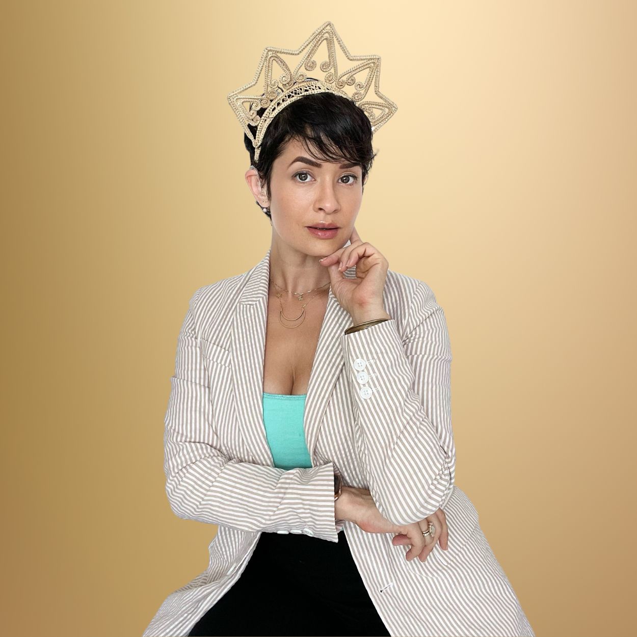 Studio portrait of Cindy Suarez, a resilient, bilaterally deaf woman and President of Crisocolla.com. She offers plant-based, custom hair care solutions in Puerto Rico. Dressed in a creamy, sand-striped blazer with a turquoise tank top underneath, she radiates confidence and elegance. A unique crown made from iraca palm, handcrafted by Colombian artisans, adorns her short, dark brown pixie cut. Her makeup is natural, highlighting her inherent beauty and strength.